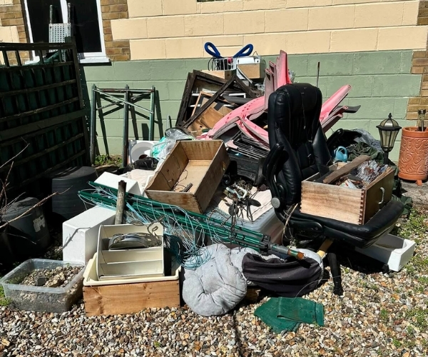 Garden area cluttered with furniture, boxes, planters and unwanted outdoor items before a Morris Movers garden clearance in Thanet.