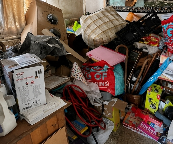 Bedroom heavily cluttered with boxes, bags, household goods and furniture before a Morris Movers house clearance in Thanet.